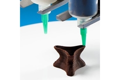 Image 3D printer extruding chocolate to create a star-shaped confection.